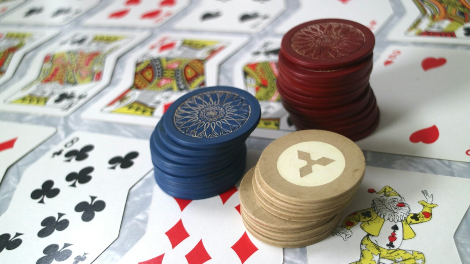Guide to Online Casino Singapore Real Money Gaming Stacked colorful casino poker chips and playing cards on a green felt gaming table (Photo by Nik Korba on Unsplash)